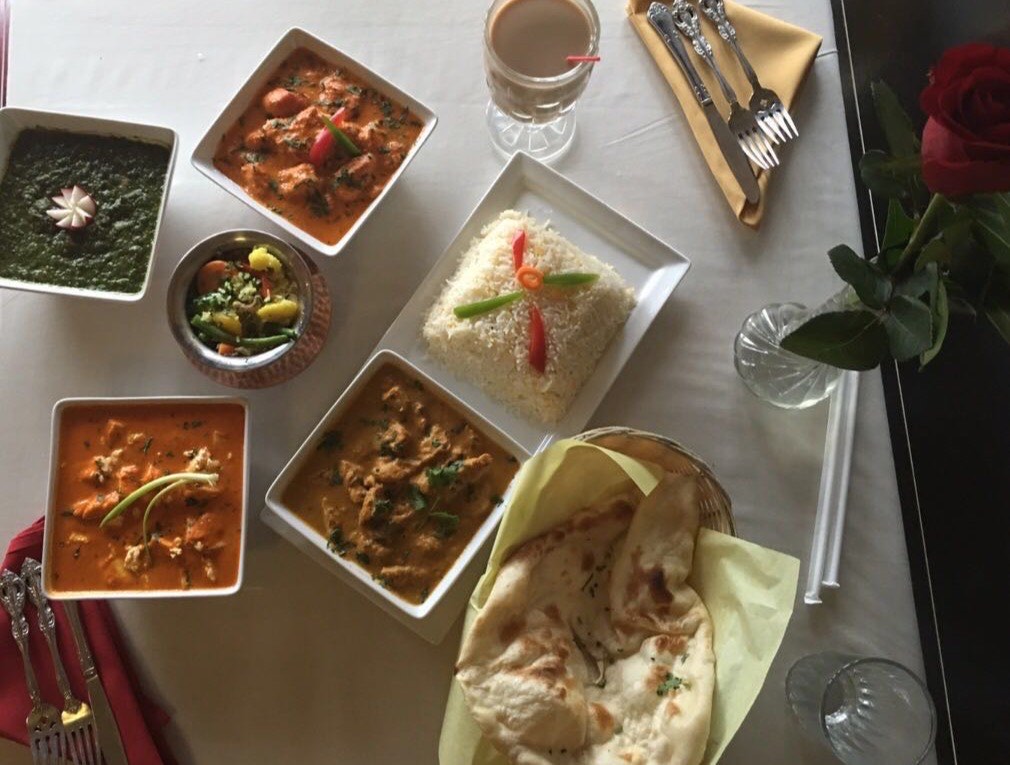 Overhead view of the table laid with curries, naan and rice